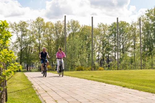 two people riding bikes down a path in a park at Othmar Herberg in Ootmarsum