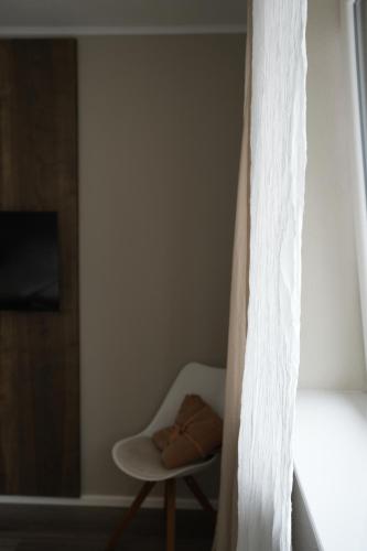 a bedroom with a white chair and a window at lantliv in Wiesmoor