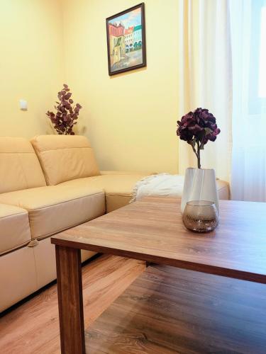 a living room with a table with a vase of flowers at APARTAMENT PLAC KATEDRALNY in Tarnów
