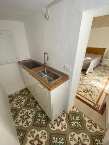 una cocina con fregadero en una habitación con cama en Dimora Quarto, en Monopoli