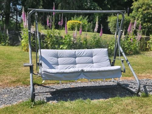 a swing in a garden with a white couch at Iris Cottage in Ráistín