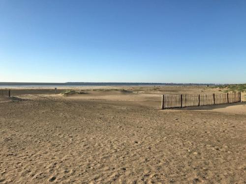 une plage de sable avec une clôture et l'océan dans l'établissement La plage - Les pins ! à 300 m de la plage, à Saint-Brévin-les-Pins