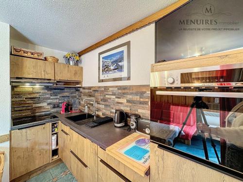 une cuisine avec des armoires en bois et un comptoir dans l'établissement Les Bruyères - 2 pièces 4 pers. - Ski aux pieds, balcon, emplacement idéal, proche commerces - FR-1-178-99, aux Menuires
