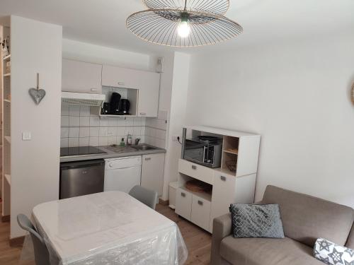 Il dispose d'une cuisine et d'un salon avec un canapé et une table. dans l'établissement Charmant appartement 4 pers,vue montagne avec parking privé et balcon, à Cauterets