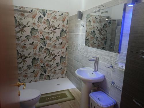 a bathroom with a sink and a toilet and a mirror at Simbilis B&B Holiday Experience bouganville in Quartu SantʼElena