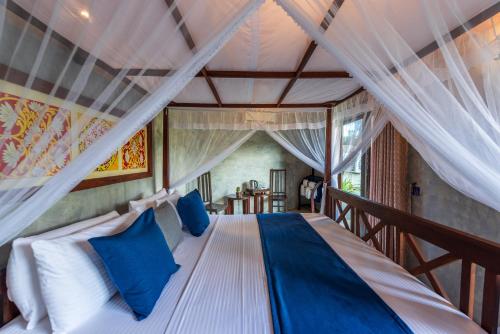 a bedroom with a bed with blue pillows at Anama by Queens Mount in Tangalle