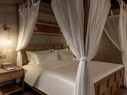 a bedroom with a white bed with curtains at 九寨云裳 in Jiuzhaigou