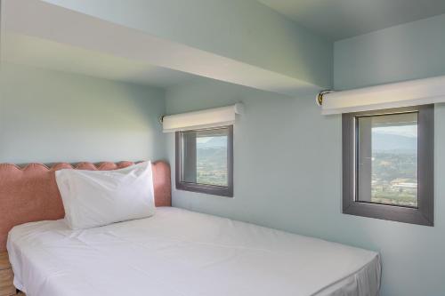 a bed in a room with two windows at Māat Villa in Heraklio Town