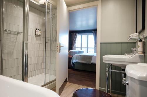 a bathroom with a shower and a sink and a bed at The Pilgrim Inn in Southampton