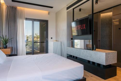 a bedroom with a large white bed and a tv at Māat Villa in Heraklio Town