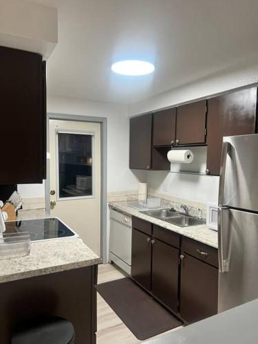 a kitchen with brown cabinets and a stainless steel refrigerator at Beautiful downtown Anchorage 2 in Anchorage