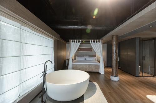 a bathroom with a bath tub and a bed at 九寨云裳 in Jiuzhaigou