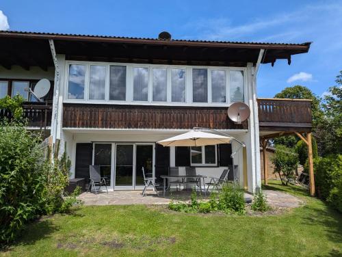ein Haus mit einer Terrasse und einem Sonnenschirm in der Unterkunft Garten 2-Zimmer WHG in Bestlage in Rottach-Egern, 400m vom See in Rottach-Egern