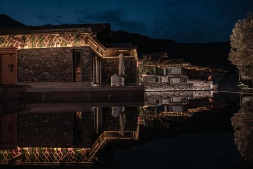 a house with lights on the water at night at 九寨云裳 in Jiuzhaigou