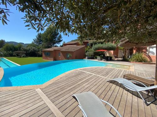 - une piscine avec 2 chaises sur une terrasse en bois dans l'établissement La Maison Du Castellet, au Castellet