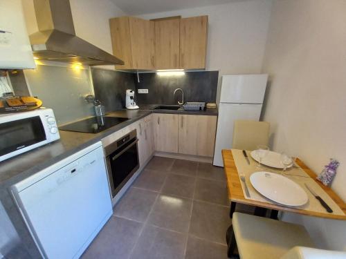 a small kitchen with a table and a microwave at Appart T3 avec Cours et Parking Privé in Montélimar