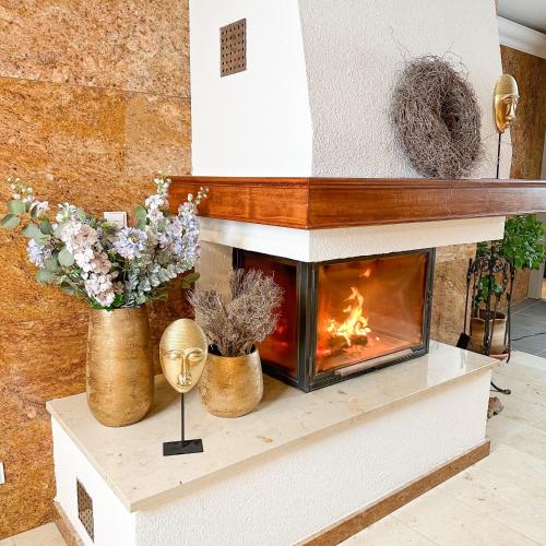 a fireplace in a living room with flowers and a mask at Lázeňský a Wellness hotel NIVAMARE in Luhačovice