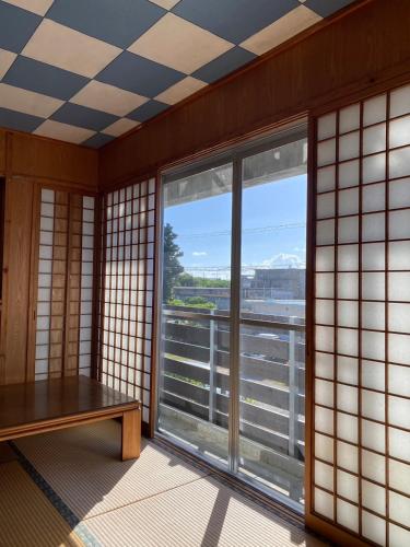 a room with a table and a large window at ゲストハウスUYokinawa in Uruma