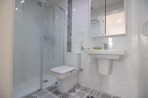 Un baño con inodoro, lavabo y ducha. en Malasaña House, en Málaga