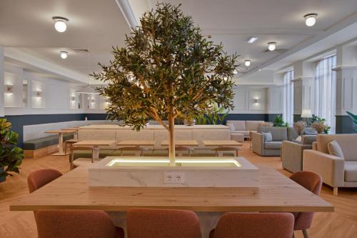 a table with a tree in the middle of a room at B&B HOTEL Figueira Da Foz in Figueira da Foz