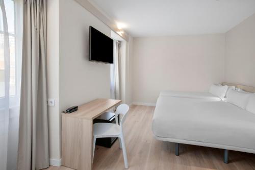 a bedroom with a bed and a desk and a bed and a bed at B&B HOTEL Figueira Da Foz in Figueira da Foz