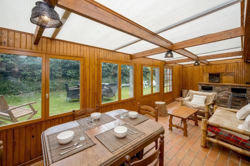 un salon avec une table, des chaises et des fenêtres dans l'établissement LEtang du Vaudic - Jardin de 1000m², à Pordic