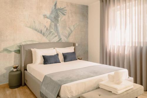 ein Schlafzimmer mit einem großen weißen Bett mit blauen Kissen in der Unterkunft Glam House no coração da cidade in Faro