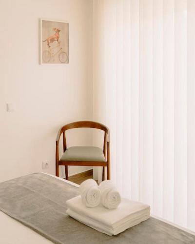 a bedroom with a chair and a bed with towels at Glam House no coração da cidade in Faro