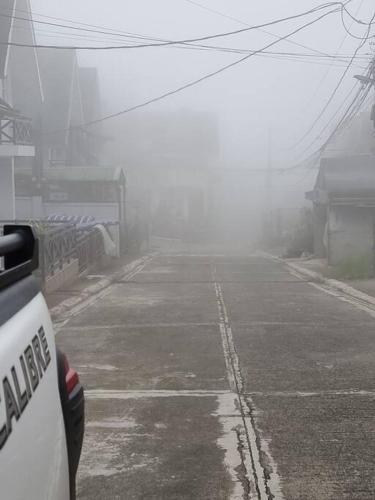 a foggy street with a car parked on the side at Bed and Breakfast Small Cozy Room with Balcony, T&B, Fast WiFi, Netflix in Baguio