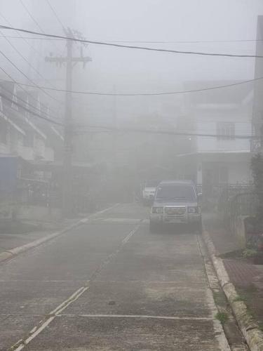 a truck driving down a street in the fog at Bed and Breakfast Small Cozy Room with Balcony, T&B, Fast WiFi, Netflix in Baguio