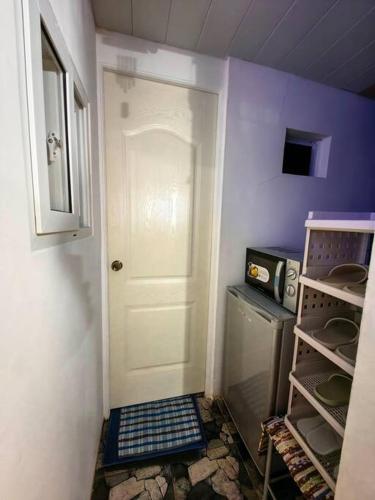 a kitchen with a white door and a stove at Bed and Breakfast Small Cozy Room with Balcony, T&B, Fast WiFi, Netflix in Baguio