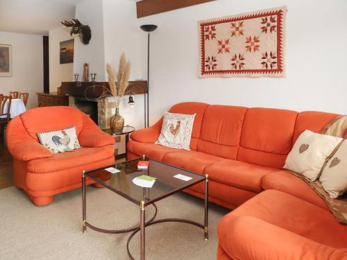a living room with two orange couches and a table at Apartment Lichen 4 by Interhome in Verbier