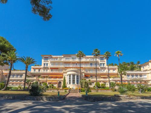 un grand bâtiment avec des palmiers devant dans l'établissement Apartment Mont des Oiseaux-2 by Interhome, à Hyères