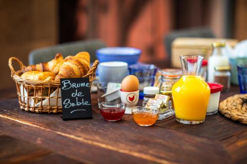 a table with a basket of bread and a basket of orange juice at Domaine de Campagnac - Spa & Sauna in Carsac-Aillac