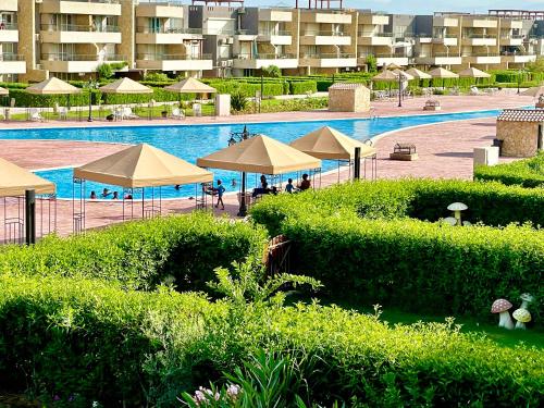 a swimming pool with umbrellas and a resort at شاليه للايجار عائلات فقط 3 غرف نوم مكيف بالكامل قرية بلومار السخنة Blumar Elsokhna العين السخنة in Ain Sokhna
