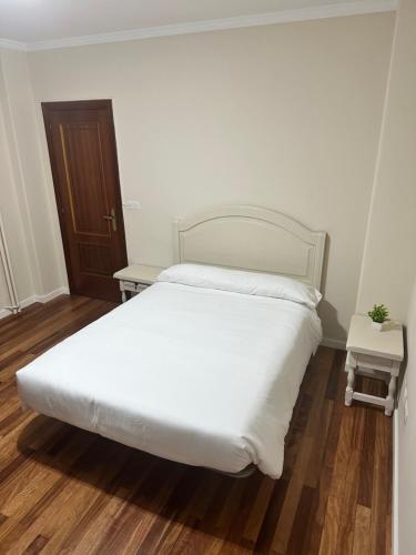 Schlafzimmer mit einem weißen Bett und Holzboden in der Unterkunft Alojamiento en el corazón de Monforte de Lemos en Ribeira Sacra in Monforte de Lemos