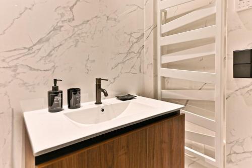 La salle de bains est pourvue d'un lavabo et d'un mur en marbre. dans l'établissement Magnifique Appartement #Miromesnil #Monceau #Paris, à Paris