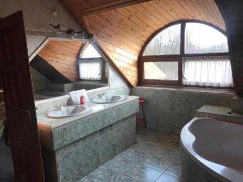 a bathroom with two sinks and a bath tub at Koppány Fogadó in Báthorikert