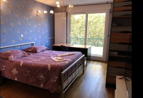 une chambre avec un lit, un bureau et une fenêtre dans l'établissement Appartement avec vue sur le parc de la tête d'or, à Lyon