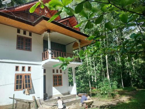 a white house with a porch and a balcony at Sugi House Toraja - Penginapan Villa Harian Keluarga -Muat 20 orang in Rantepao