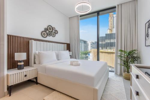 a bedroom with a large white bed and a large window at STAY BY LATINEM Luxury 2BR Holiday Home W204 near Burj Khalifa in Dubai