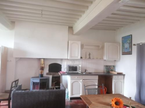 a kitchen with white cabinets and a table in a room at Natur und Sterne in Arleuf