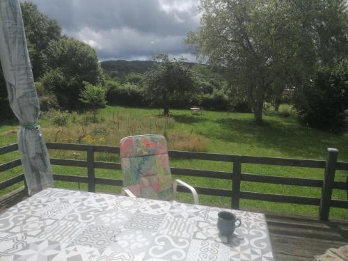 a table and a chair on a deck with a view of a field at Natur und Sterne in Arleuf