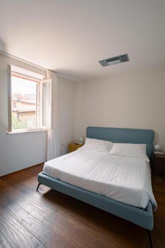 a bedroom with a bed with a blue headboard and a window at Urbino Apartment - Urban Retreat in Urbino
