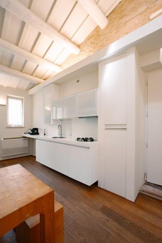 a kitchen with white cabinets and a wooden floor at Urbino Apartment - Urban Retreat in Urbino