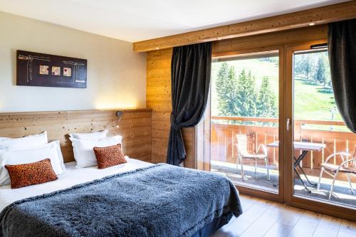 a bedroom with a bed and a balcony at Hôtel Restaurant "Les Sapins" Wellness & Gourmet in Manigod