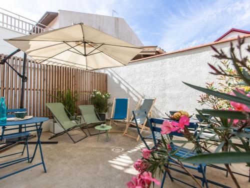 un patio avec tables, chaises et un parasol dans l'établissement Apartment Cap Océan-9 by Interhome, à Capbreton