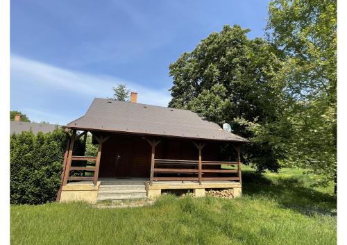 a wooden cabin with a roof in a field at Areál Kamínka - SRUB in Roštín