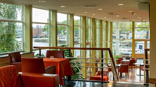 a restaurant with tables and chairs and windows at Pension Homeland in Amsterdam