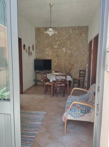 a living room with a table and chairs and a stone wall at L'Azzurro Apartment in Valderice